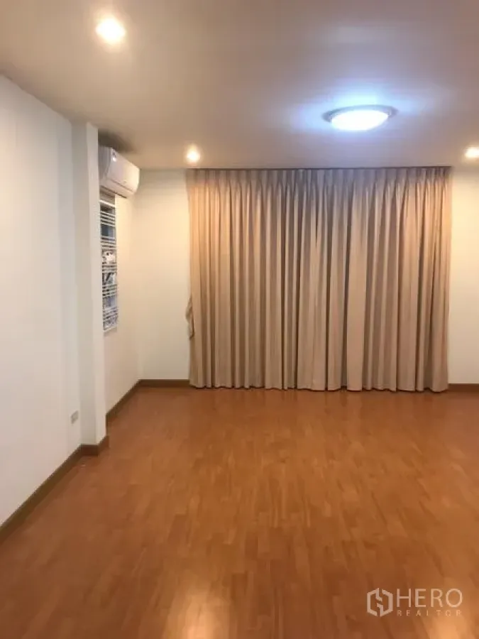 独立式住宅 出租在Din Daeng, Bangkok - 空房间，木纹地板、米色窗帘、筒灯和壁挂空调。