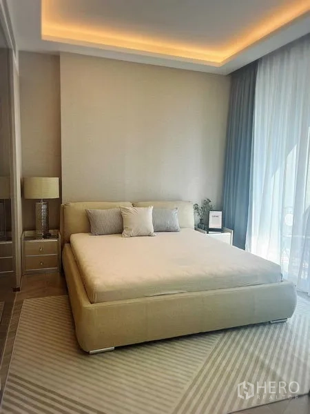 Condominium for rent in Khlong Toei, Bangkok - Serene bedroom with king bed, cove lighting, and floor-to-ceiling curtains.