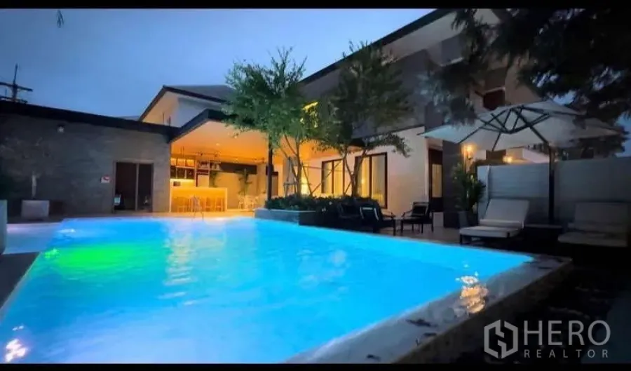 Detached House for sale in Bang Lamung, Chon Buri - Night shot of the house showing glowing pool, sun loungers and warm outdoor lighting.