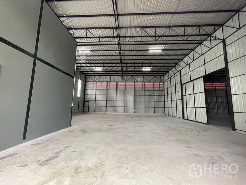 Warehouse for rent or sale in Lam Luk Ka, Pathum Thani - Spacious warehouse interior in Lam Luk Ka with high steel truss roof, LED lighting and smooth concrete floor.