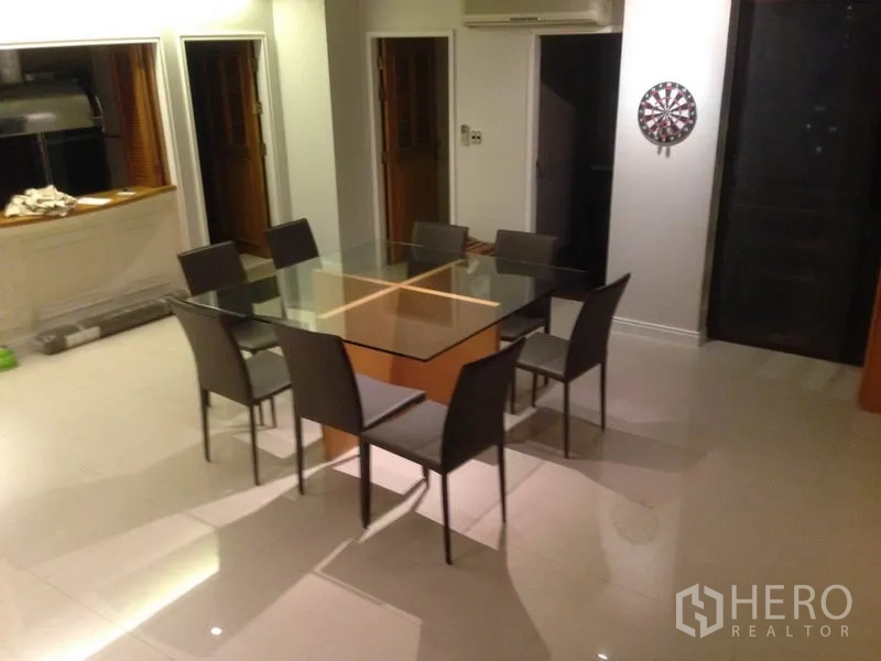 Condominium for rent in Bang Rak, Bangkok - Dining area featuring a square glass table for six beside a kitchen pass‑through.