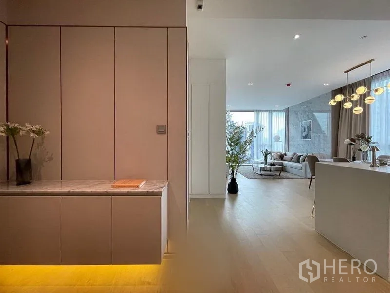 Condominium for rent in Watthana, Bangkok - Entry hallway with built-in cabinets and warm lighting leading to an open-plan living and dining area.