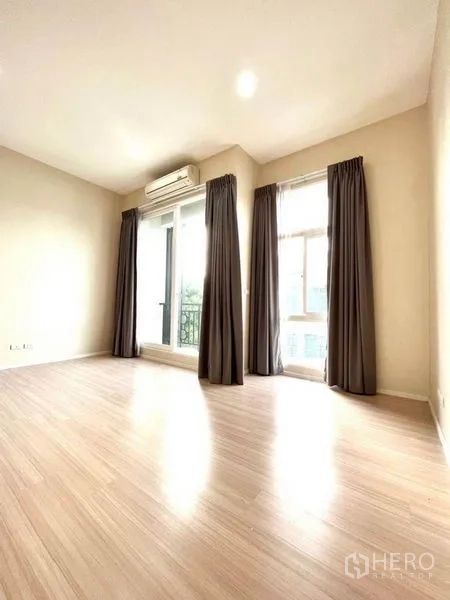Townhouse for sale in Bang Kapi, Bangkok - Corner bedroom with balcony door, multiple windows, air conditioner, and wood-style floors.