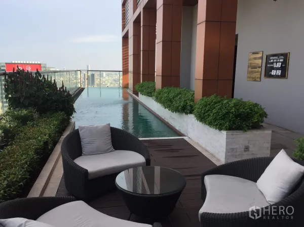 公寓 出租在Bang Rak, Bangkok - 屋顶无边泳池配玻璃栏杆与绿植，设户外休闲座椅，俯瞰城市天际线。