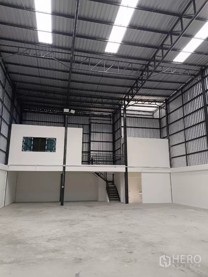 Warehouse for rent in Bang Phli, Samut Prakan - High-ceiling warehouse interior with a mezzanine office and steel staircase.
