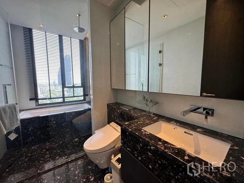Condominium for rent - Bathroom with black marble vanity, shower area, and window to skyline views.