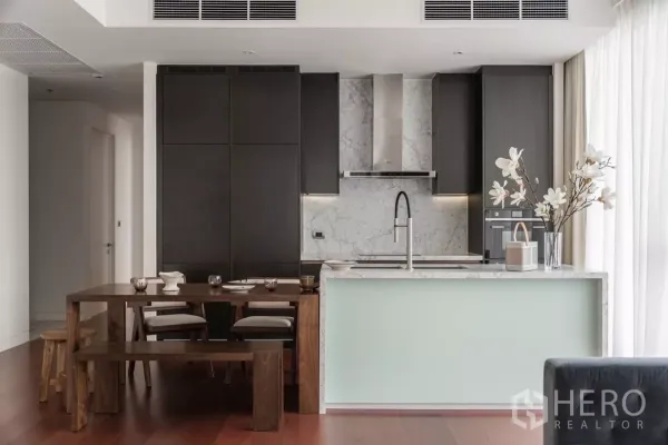 公寓 出租在Watthana, Bangkok - 现代厨房，大理石挡板、深色橱柜与木质长椅餐桌。