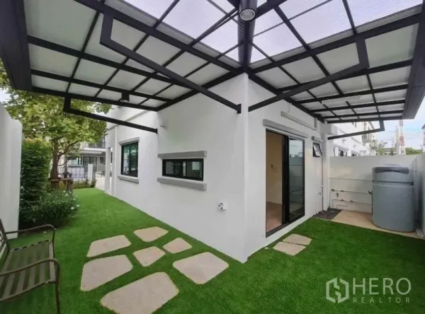 Townhouse for rent in Bang Phli, Samut Prakan - Covered side yard with artificial grass, stepping stones, sliding glass door and water tank.