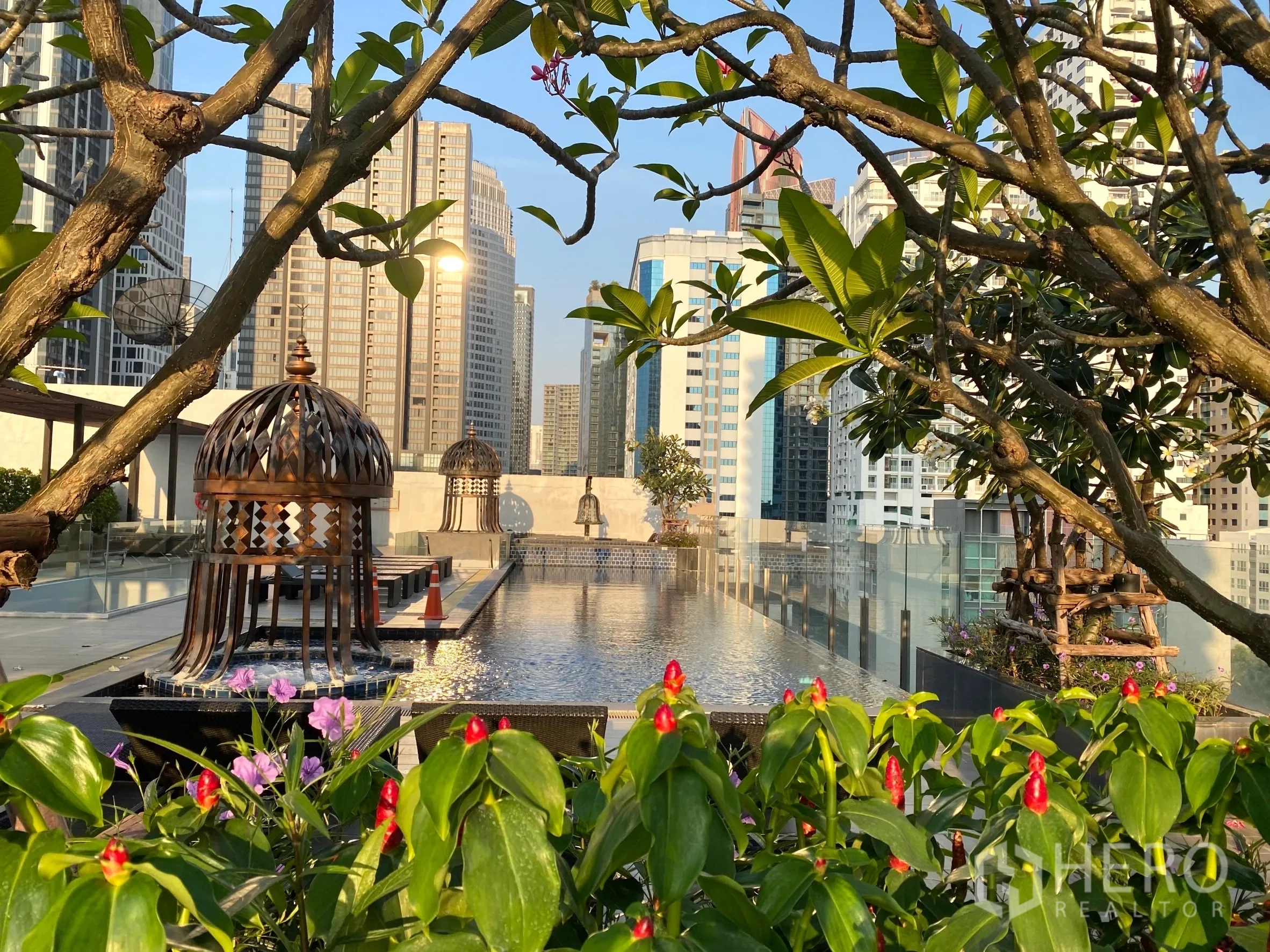 Condominium for rent in Watthana, Bangkok - Rooftop infinity pool with city skyline views, lush planters, and sun loungers.