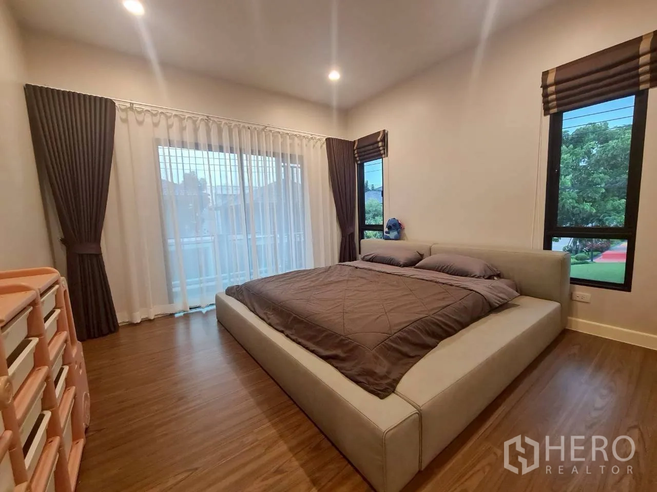 Detached House for rent or sale in Lam Luk Ka, Pathum Thani - Spacious master bedroom with king bed, sliding doors to the balcony and dual-aspect windows.