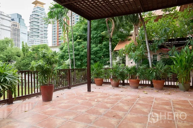Detached House for rent in Watthana, Bangkok - Large shaded terrace with terracotta tiles, potted plants and a city skyline backdrop.