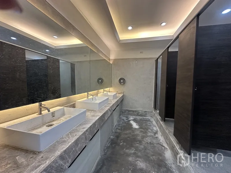 Retail Space for rent in Bang Rak, Bangkok - Modern restroom with long stone countertop, vessel sinks, large mirror, and stalls.