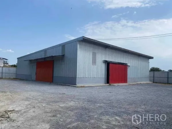 Warehouse for rent in Nong Khaem, Bangkok - Metal-clad warehouse with two red sliding doors and a large gravel yard in Nong Khaem, Bangkok.