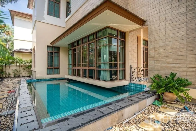 独立式住宅 出租在Watthana, Bangkok - 泳池转角环绕房屋，窗墙伸出至水面上方。