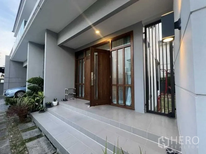 独立式住宅 出租在Mueang Nonthaburi, Nonthaburi - 有顶前廊，木质入户门与台阶及壁灯。
