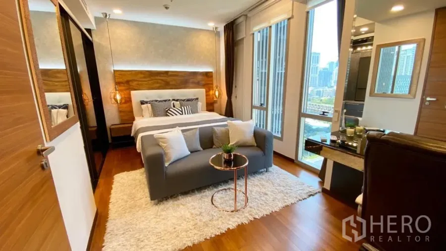 Condominium for sale in Khlong Toei, Bangkok - Spacious bedroom with king bed, small sofa, large windows and skyline outlook.