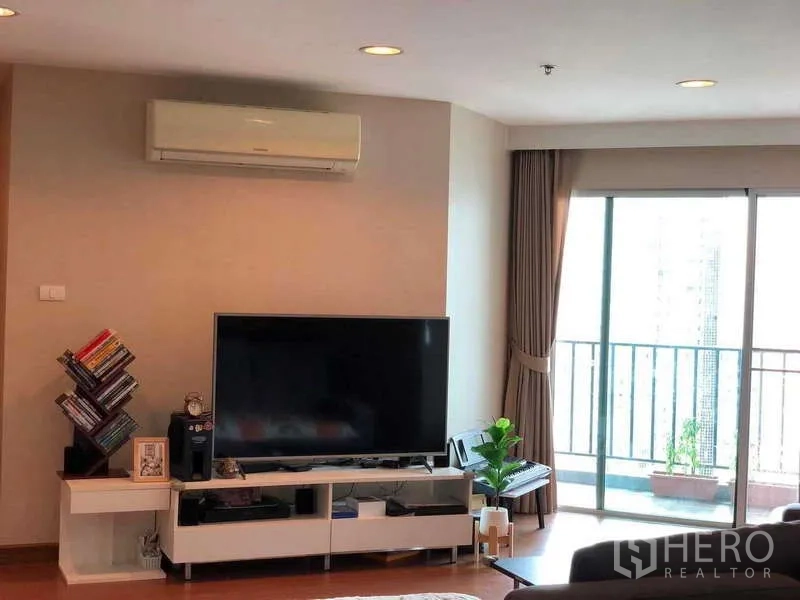 คอนโด ขายในHuai Khwang, Bangkok - ผนังทีวีจอใหญ่ ชั้นหนังสือ และประตูกระจกบานเลื่อนเชื่อมระเบียง