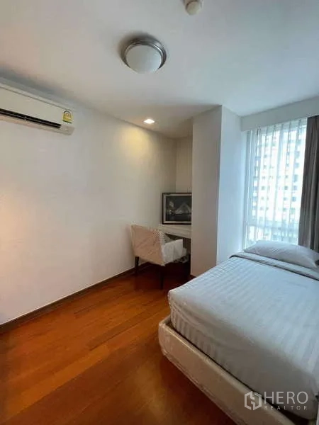 Condominium for sale in Watthana, Bangkok - Bright second bedroom with large window, bed and study nook.