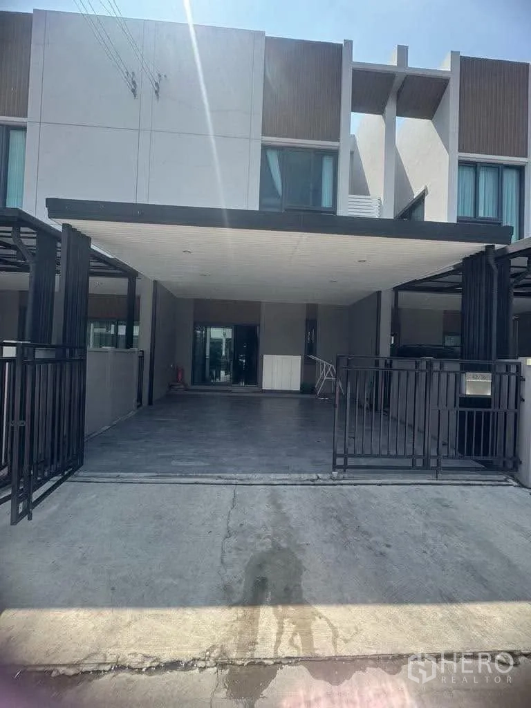 Townhouse for rent in Bang Kapi, Bangkok - Modern two-storey townhouse exterior with gated driveway and canopy.
