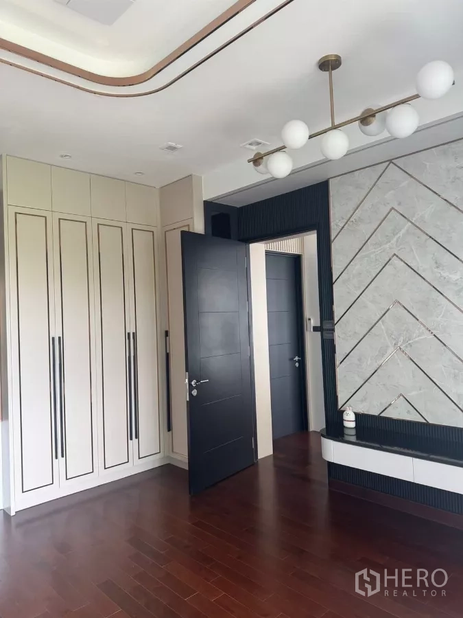 Detached House for rent in Lat Krabang, Bangkok - Bedroom corner featuring built-in wardrobes, a feature wall and modern pendant lighting.