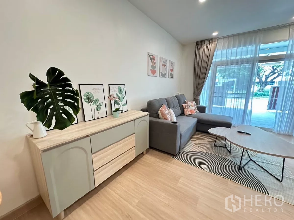 联排别墅 出租在Bang Phli, Samut Prakan - 客厅设有边柜与落地推拉门，面向花园景观。