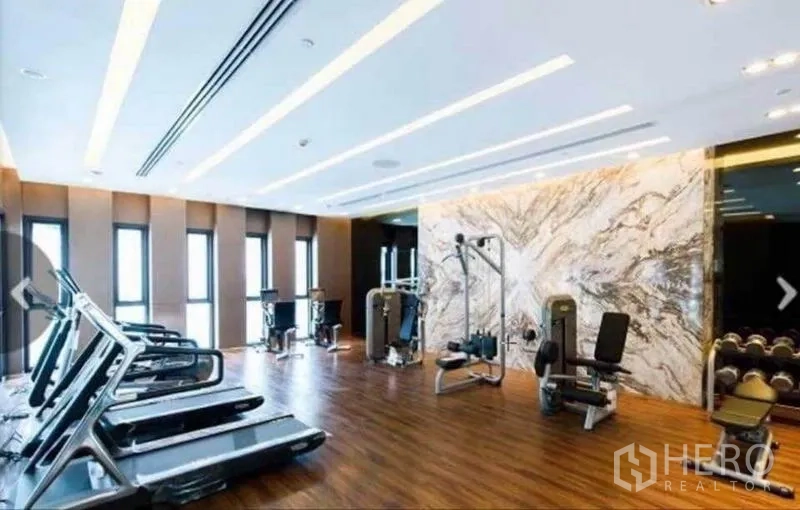 Condominium for rent in Watthana, Bangkok - Fitness gym with treadmills, weight machines, and wood floors.
