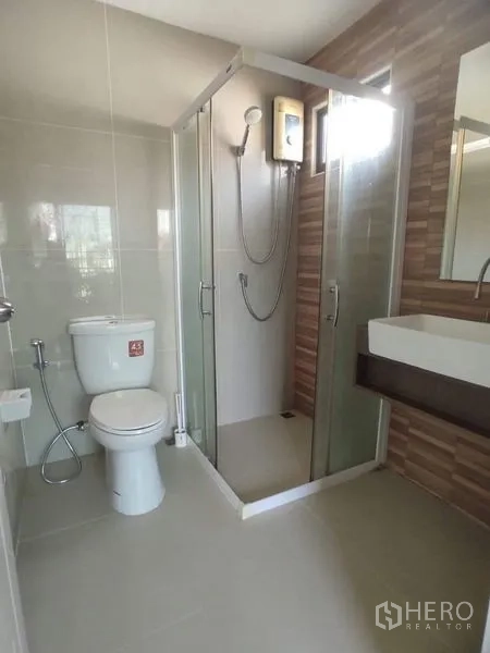 Townhouse for rent - Modern bathroom with glass shower enclosure, water heater, vanity and toilet.