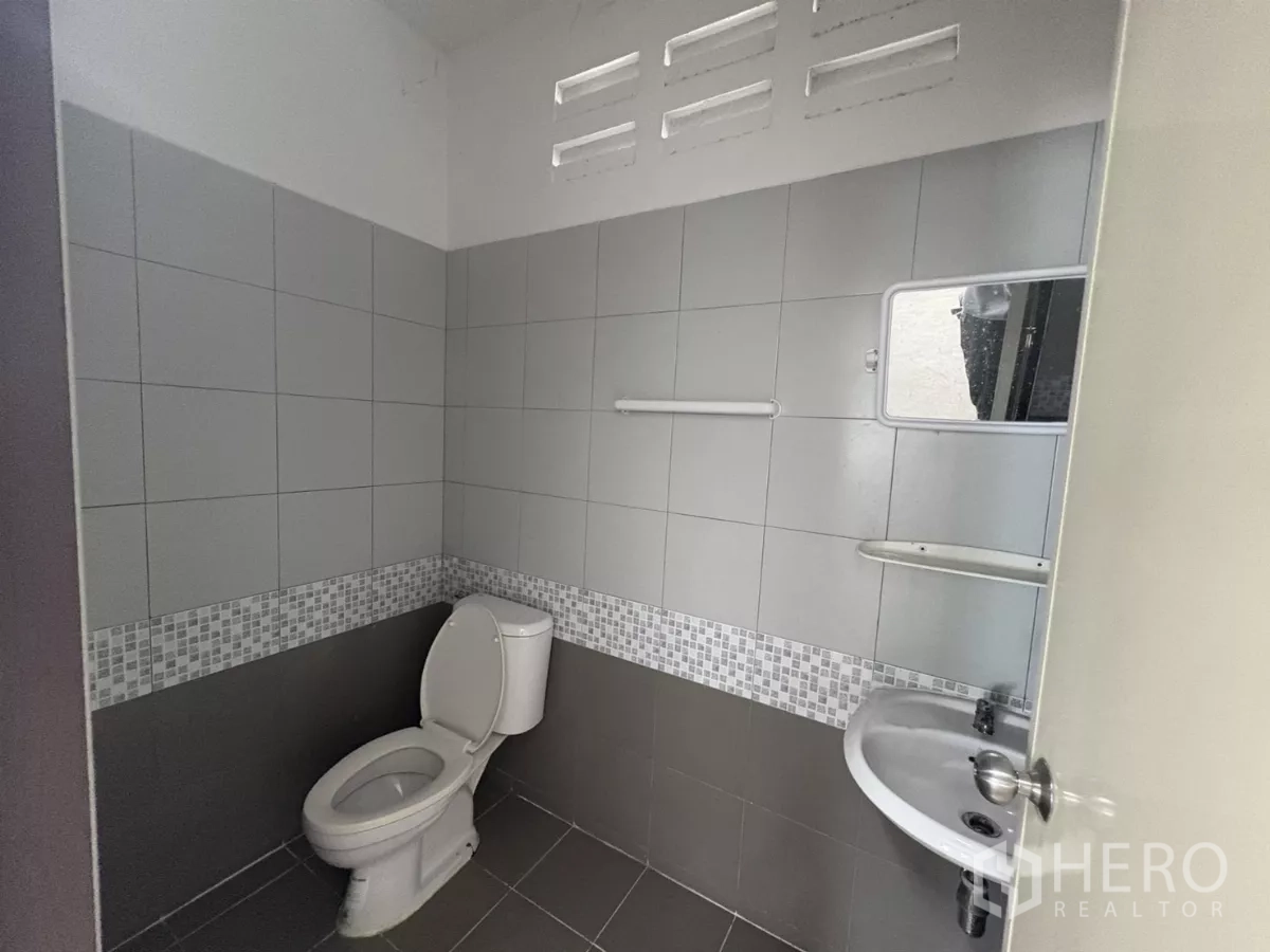Factory for rent in Phra Samut Chedi, Samut Prakan - Clean tiled restroom with toilet, sink and ventilation blocks.
