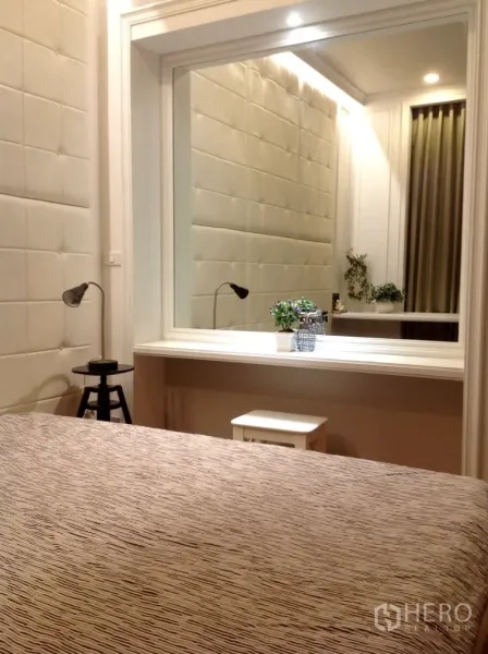 公寓 出租在Watthana, Bangkok - 卧室配软包墙、大幅框镜与白色梳妆台，灯光柔和。