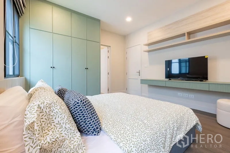 Detached House for sale in Saphan Sung, Bangkok - Bedroom view toward TV unit and floating shelves opposite green wardrobes.