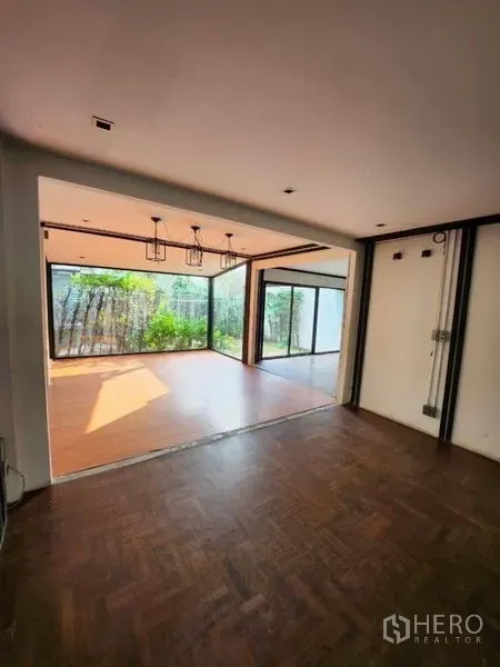 Home Office for rent in Lat Phrao, Bangkok - Open studio space with pendant lights and floor-to-ceiling sliding glass opening to a garden terrace.