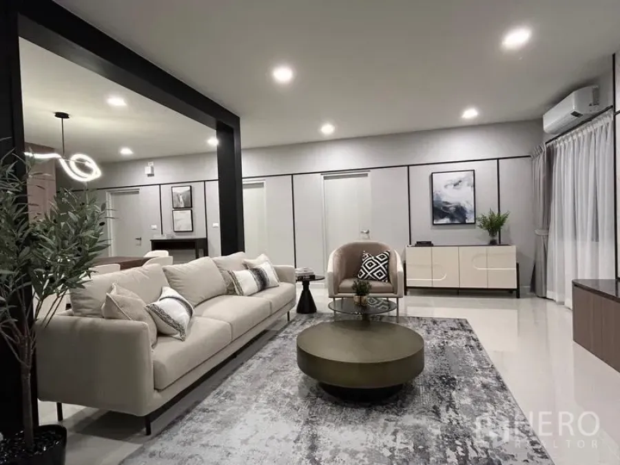 Detached House for rent or sale in Bang Phli, Samut Prakan - Modern living room with neutral sofa set, round tables, indoor plant and soft lighting.