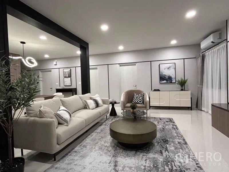 Detached House for rent or sale in Bang Phli, Samut Prakan - Modern living room with neutral sofa set, round tables, indoor plant and soft lighting.