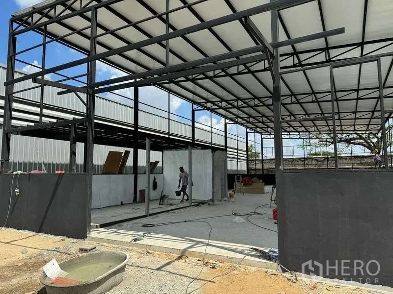 Warehouse for rent in Mueang Pathum Thani, Pathum Thani - Steel-frame warehouse under construction with high roof and concrete floor.