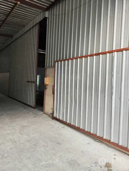 货栈 出租在Bang Kapi, Bangkok - 邦甲比仓库入口，带大型金属推拉门与波纹金属外墙。