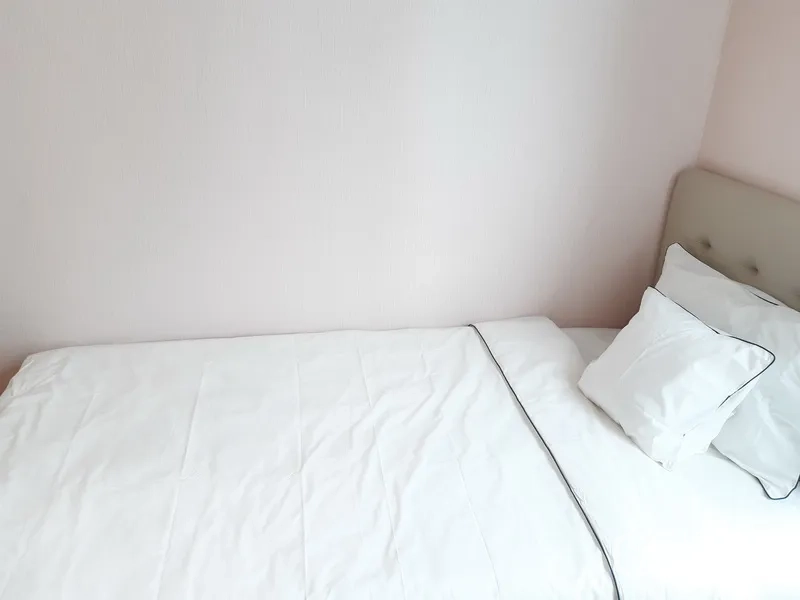 公寓 出租在Watthana, Bangkok - 白色床品的单人床靠浅色墙面特写。