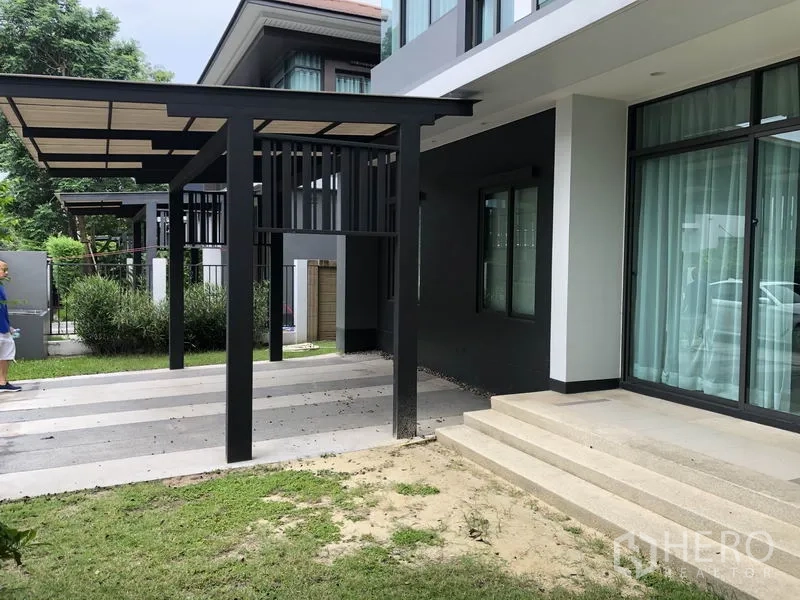 Detached House for rent in Bang Kapi, Bangkok - Modern house exterior with covered carport, steps to patio and small lawn.