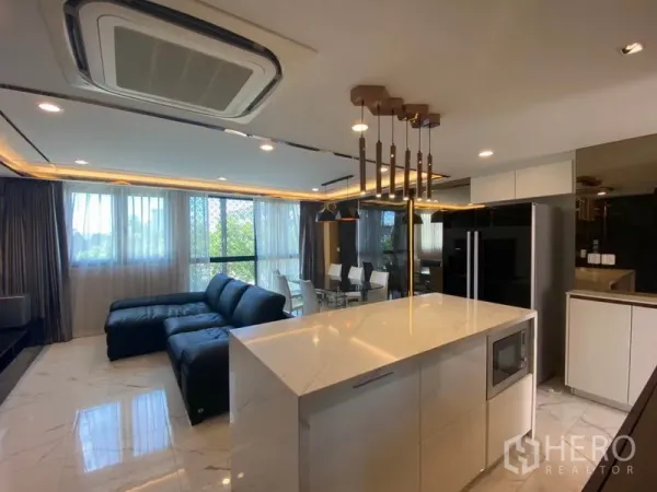 Townhouse for sale in Yan Nawa, Bangkok - Open‑plan living area with marble floors, a black sectional sofa and a sleek island kitchen under pendant lights and large windows.