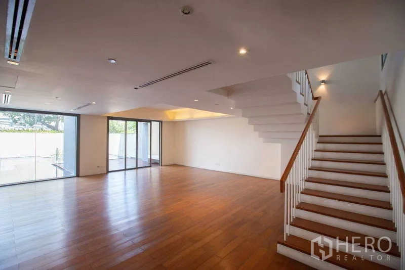 Condominium for rent in Yan Nawa, Bangkok - Expansive living area with staircase and sliding doors to the pool terrace.