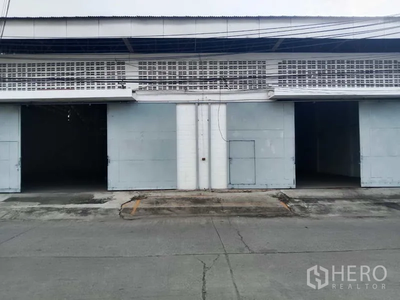 Factory for rent in Samut Prakan - Factory exterior with two wide sliding metal doors and loading bays.