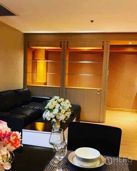 Condominium for rent in Watthana, Bangkok - Dining table set looking toward lounge with built‑in shelving and sliding doorway.