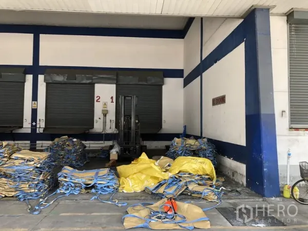 Warehouse for rent in Phra Nakhon Si Ayutthaya - Close-up of dock-high doors with a forklift area and stacked cargo slings.