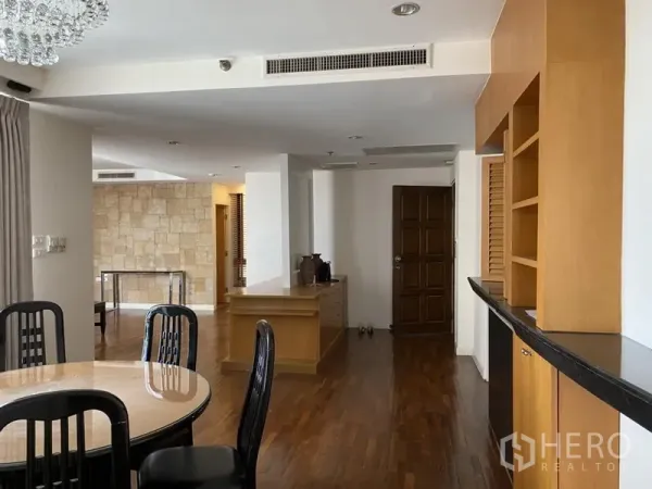 Condominium for rent or sale in Sathon, Bangkok - Open-plan dining and entry area with hardwood floors, built-in wood cabinetry and a curved countertop in a Sathon condo.