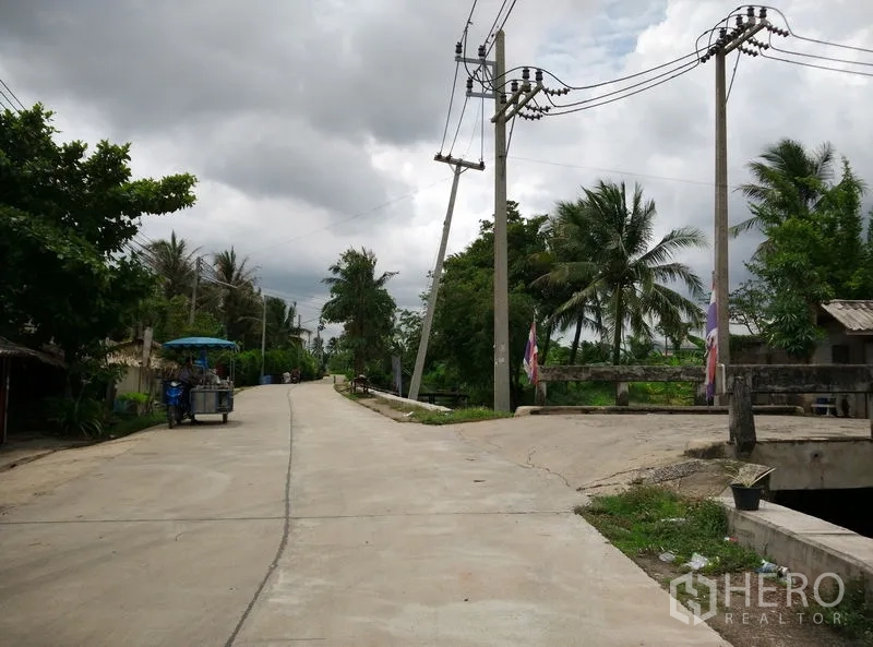 โรงงาน ให้เช่าหรือขายในKrathum Baen, Samut Sakhon - ถนนท้องถิ่นเงียบสงบ มีเสาไฟฟ้าและสะพานข้ามคลอง ท่ามกลางต้นไม้เขียวขจี
