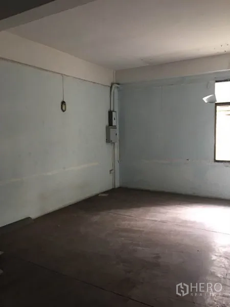 Shophouse for rent in Khlong Toei, Bangkok - Open storage or work area with a window and unfinished flooring.