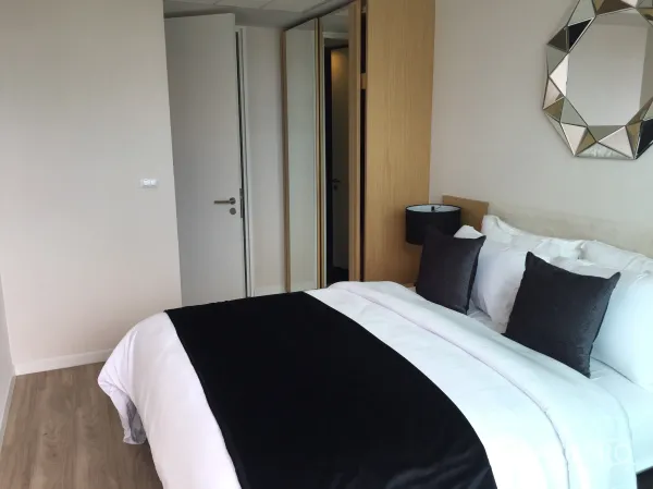 Condominium for sale in Bang Rak, Bangkok - Second bedroom with built-in wardrobe, wood floors and neutral decor.