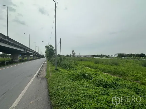 ที่ดิน ขายในSai Mai, Bangkok - ด้านหน้าแปลงติดถนนข้างทางยกระดับ มีเสาไฟฟ้าและพื้นที่ว่างฝั่งขวา เขตสายไหม