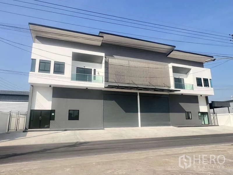 Warehouse for rent or sale - Modern two-storey warehouse facade with dual roller shutters, balconies and a wide driveway.