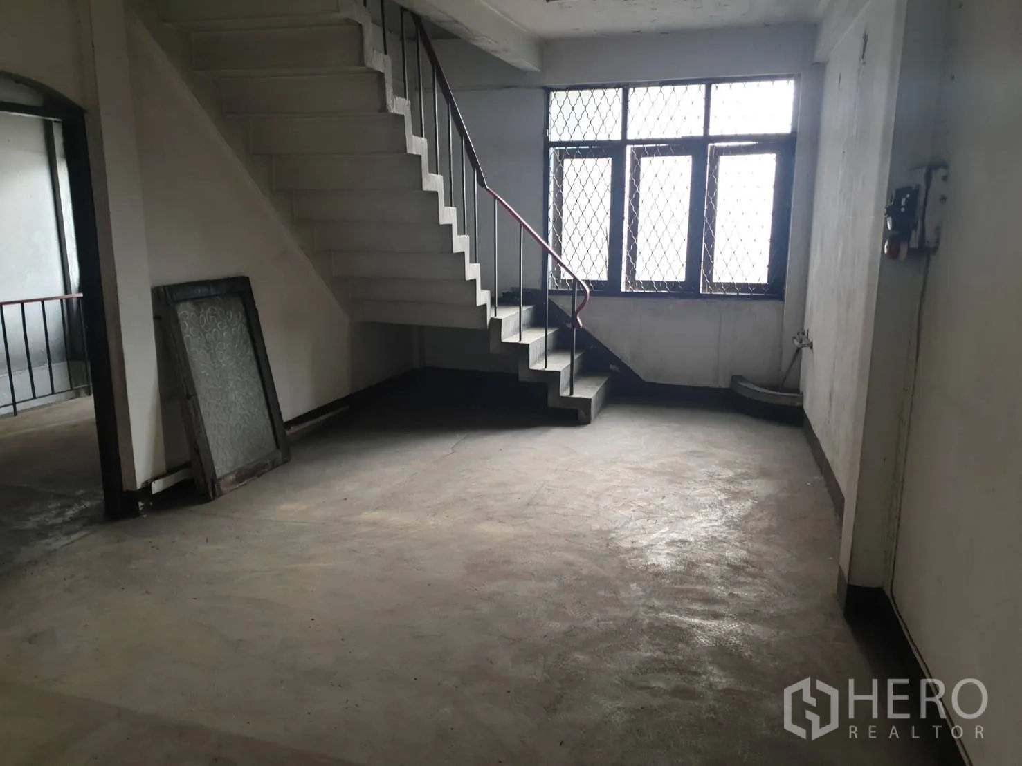 店屋 出租在Phra Khanong, Bangkok - 室内楼梯与平台，金属扶手与窗户为楼层引入自然光。