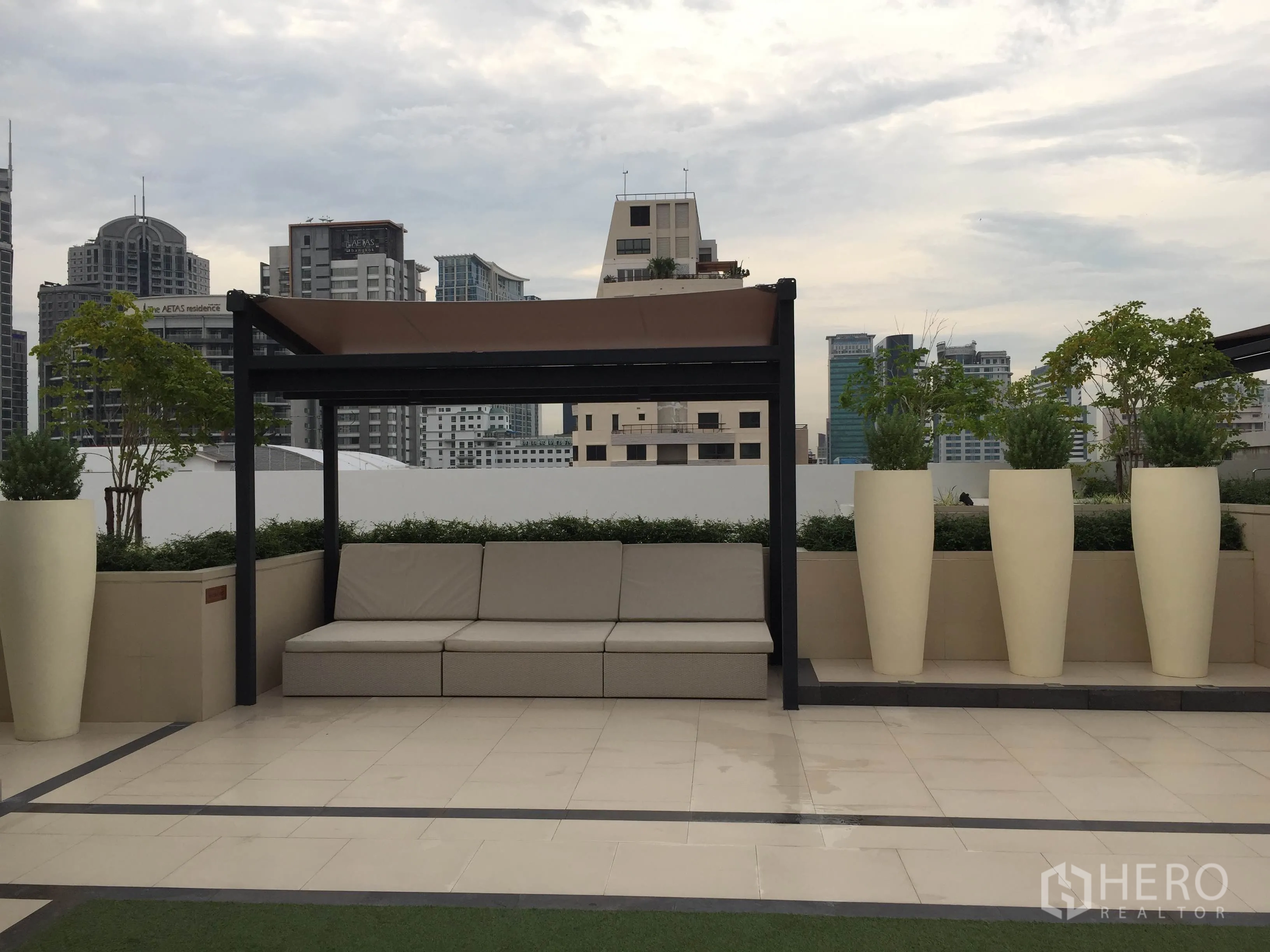 公寓 出租在Pathum Wan, Bangkok - 屋顶露台，带顶棚休闲座位、高大花盆与城市天际线景观。